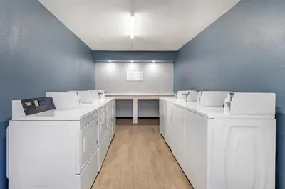 a room with white washing machines and a table at Suburban Studios International Drive in Orlando