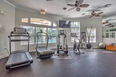 a gym with several tread machines and a ceiling fan at Palm Key Villa 7 bed on Emerald Island Resort in Kissimmee