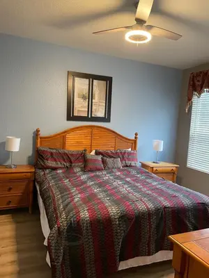 a bedroom with a bed with a plaid comforter and two tables at Windsor Hills Resort 5BR Villa, Amenities, Private Pool & Water Park, Near Disney, Sea World, Universal in Orlando