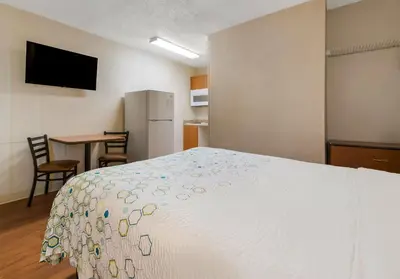 a bedroom with a bed and a table with chairs at HomeTowne Studios by Red Roof Orlando - UCF Area in Orlando