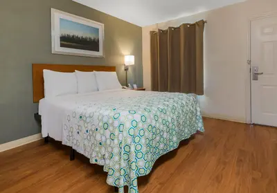 a bedroom with a bed and a window and a door at HomeTowne Studios by Red Roof Orlando - UCF Area in Orlando