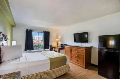 a hotel room with a bed and a flat screen tv at OYO Hotel Orlando Airport in Orlando