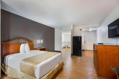 a bedroom with a large bed and a kitchen at OYO Hotel Orlando Airport in Orlando