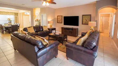 a living room with leather furniture and a flat screen tv at Minnie and Mickeys Mansion - Emerald Island in Kissimmee