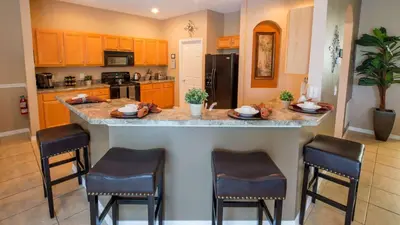 a kitchen with a large island with bar stools at Minnie and Mickeys Mansion - Emerald Island in Kissimmee