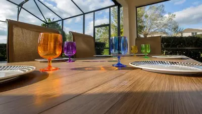 a wooden table with wine glasses and plates on it at Minnie and Mickeys Mansion - Emerald Island in Kissimmee