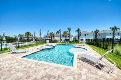 a swimming pool with two chairs and a patio with a fence at Welcoming Home With Air Hockey Table And Waterpark & Resort Access Near Disney At Encore Resorts Reunion - 321Bu in Kissimmee