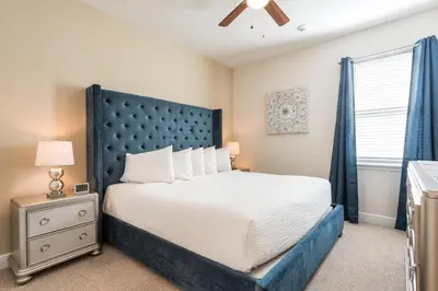 a bedroom with a large bed with a blue headboard at Spectacular Home With Theater, Theme Rooms Near Disney With Waterpark & Resort Access At Encore Resort - 7734Gr in Kissimmee