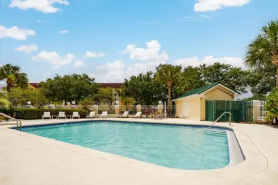 a large swimming pool with chairs and trees at Country Inn & Suites by Radisson, Orlando Airport, FL in Orlando