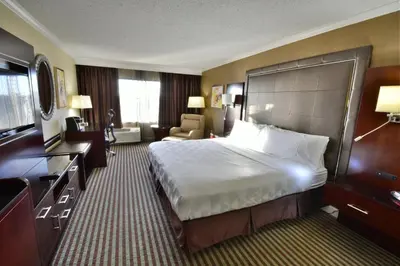 a hotel room with a large bed and a chair at Holiday Inn Orlando East-UCF Area by IHG in Orlando