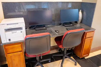 a desk with two computer monitors and two chairs at Holiday Inn Orlando East-UCF Area by IHG in Orlando