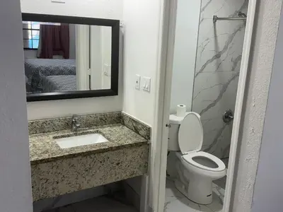 a bathroom with a toilet and a sink and a mirror at Apollo Inn - Downtown in Kissimmee