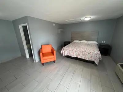 a bedroom with a bed and an orange chair at Apollo Inn - Downtown in Kissimmee