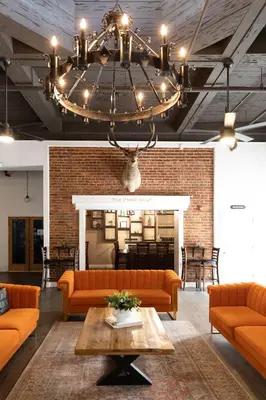a living room with orange couches and a chandelier at Hunter Arms Hotel in Saint Cloud