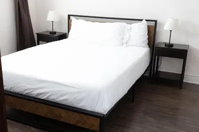 a large bed with white sheets and two night stands at Hunter Arms Hotel in Saint Cloud