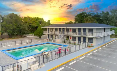 a house with a swimming pool and a parking lot at Sunshine Inn in Kissimmee