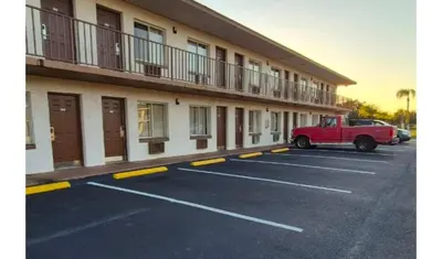 a red truck parked in a parking lot in front of a hotel at Central Motel Kissimmee Near Disney World in Kissimmee