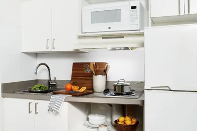 a white kitchen with a sink and a microwave at InTown Suites Extended Stay Orlando FL - Universal in Orlando