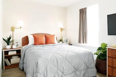a white bedroom with a bed with orange pillows at InTown Suites Extended Stay Select Orlando FL - Lee Rd in Orlando