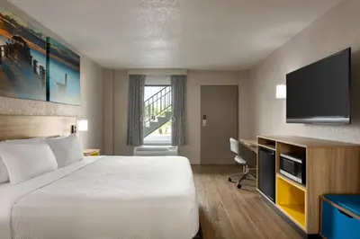 a hotel room with a bed and a flat screen tv at Days Inn by Wyndham Apopka/Orlando in Orlando