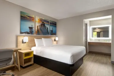 a hotel room with a bed and a sink at Days Inn by Wyndham Apopka/Orlando in Orlando