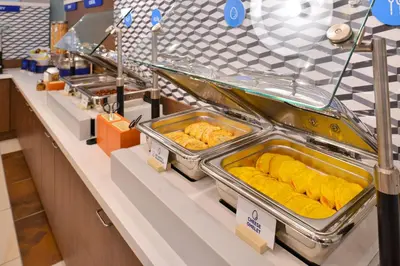 a buffet line with trays of food on display at Holiday Inn Express Hotel & Suites Orlando East-UCF Area by IHG in Orlando