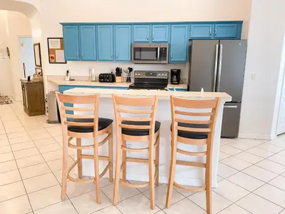 a kitchen with blue cabinets and three bar stools at Affordable Luxury Home Near Walt Disney World - Sunshine Villa at Glenbrook Resort, Orlando, Florida in Orlando