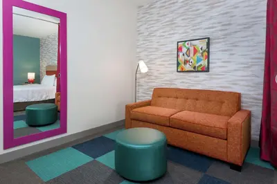 a living room with a couch and a mirror at Home2 Suites By Hilton Orlando Near UCF in Orlando
