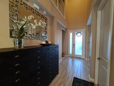 a black dresser in a hallway with a vase of flowers at 3830 Premier Villa 6Bd Private Pool and Game Room in Kissimmee