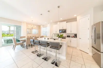 a kitchen with white cabinets and a table and chairs at Luxury Home With Themed Rooms, Air Hockey Near Disney With Waterpark & Resort Access At Encore Resort - 7699Gr in Kissimmee