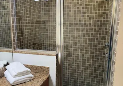 a bathroom with a shower and a sink with towels at The Point Hotel & Suites - 705S Luxury - Pool view - Close to Universal in Orlando