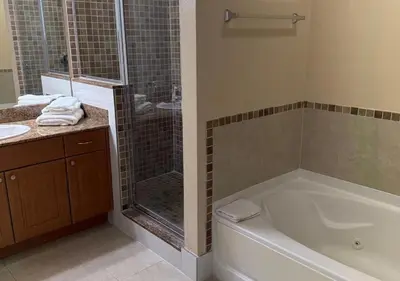 a bathroom with a shower and a tub and a sink at The Point Hotel & Suites - 705S Luxury - Pool view - Close to Universal in Orlando