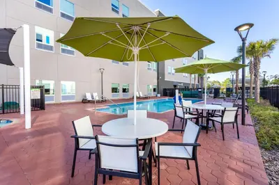 a patio with tables and chairs with umbrellas and a pool at La Quinta Inn & Suites by Wyndham Orlando I-Drive Theme Parks in Orlando