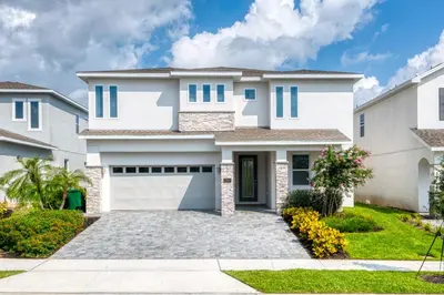 a white house with a garage at Magnificent Home Near Disney With Theater Room, Pool Table, Waterpark & Resort Access At Encore Resort Reunion - 7448Mr in Kissimmee