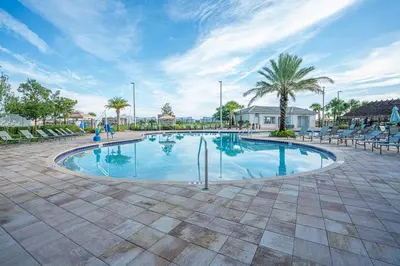 a large swimming pool with chairs and palm trees at Only 5 Miles from Disney! Free Water Park! 2 Bed, 2 Bath Condo, Sleeps 8 in Kissimmee