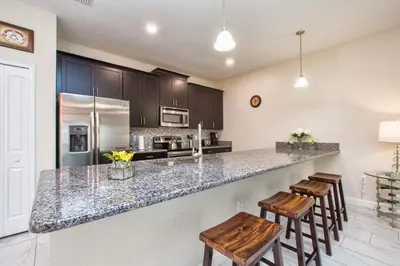 a kitchen with a counter and two stools in it at I - New 4 Bedroom Home - 5 Miles to Disney - Free Water Park - Private Pool in Kissimmee