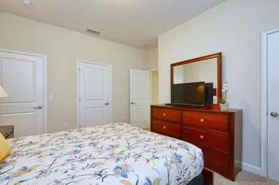 a bedroom with a bed and a dresser with a tv at I - New 4 Bedroom Home - 5 Miles to Disney - Free Water Park - Private Pool in Kissimmee