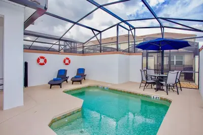 a swimming pool with a table and chairs and an umbrella at Wonderful 5 Bedroom w/ Pool Close to Disney 4801 in Kissimmee