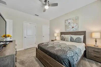 a bedroom with a bed and two lamps and a tv at Renewed Luxury Townhouse with private pool in Kissimmee