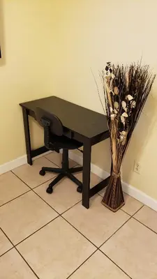 a black desk with a chair and a vase of flowers at B2 Private Room With 55