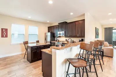 a kitchen with wooden cabinets and bar stools at Elegant Home Near Disney With Private Pool And Waterpark & Resort Access At Encore Resorts Reunion - 430La in Kissimmee