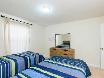 a bedroom with two beds and a dresser and a mirror at Storey Lake - Private Pool Home 10 Min to Disney in Kissimmee
