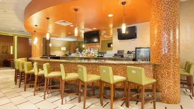 a restaurant with a bar with yellow chairs at The Florida Hotel & Conference Center in the Florida Mall in Orlando