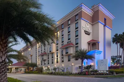 a hotel with palm trees in front of it at Delta Hotels by Marriott Orlando Lake Buena Vista in Orlando