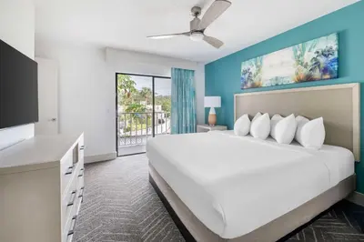 a bedroom with a large white bed and a balcony at Hilton Vacation Club Aqua Sol Orlando West in Orlando