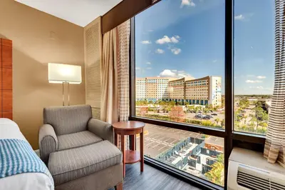 a bedroom with a bed and a chair and a large window at Best Western Orlando Gateway Hotel in Orlando