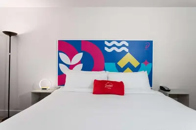 a large white bed with a red pillow on it at Howard Johnson by Wyndham Orlando Lake Buena Vista South in Kissimmee