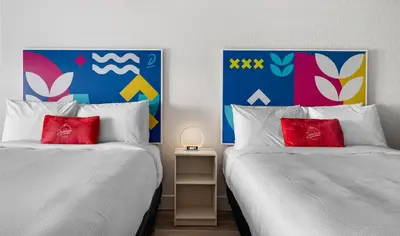 two beds with red pillows in a room at Howard Johnson by Wyndham Orlando Lake Buena Vista South in Kissimmee