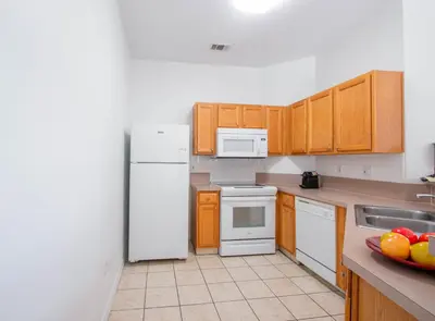 a kitchen with a white refrigerator and wooden cabinets at Berkley Lake Townhomes in Kissimmee