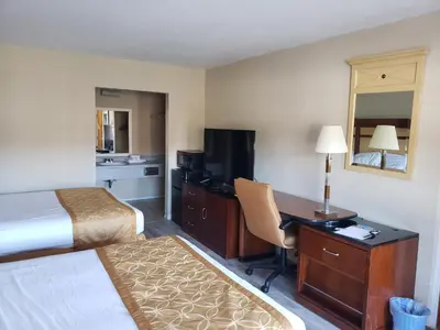 a hotel room with a bed and a desk and a bed and a room with at Knights Inn Kissimmee in Kissimmee